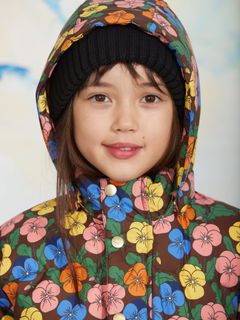 Close-up of a child wearing a heavy puffer jacket with a colorful Violas print and a black beanie.
