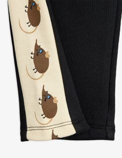 Close-up of black sweatpants featuring a cream side panel with brown Elephant shrew motifs.