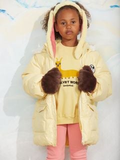 Brown faux fur mittens worn with a yellow jacket.