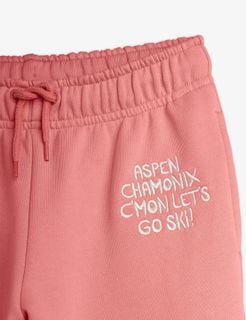 Close-up of pink sweatpants featuring a white Aspen Chamonix embroidery and an elastic drawstring waist.