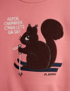 Close-up of a pink sweatshirt featuring a skiing squirrel chenille patch with text.