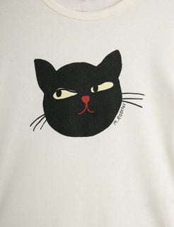 Close-up of a black cat print with a red nose on an off-white fabric.