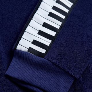 Close-up of a navy terry jacket sleeve featuring a white and black piano keys tape.