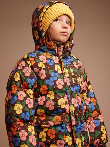 Yellow knitted ribbed hat worn with a floral puffer jacket.