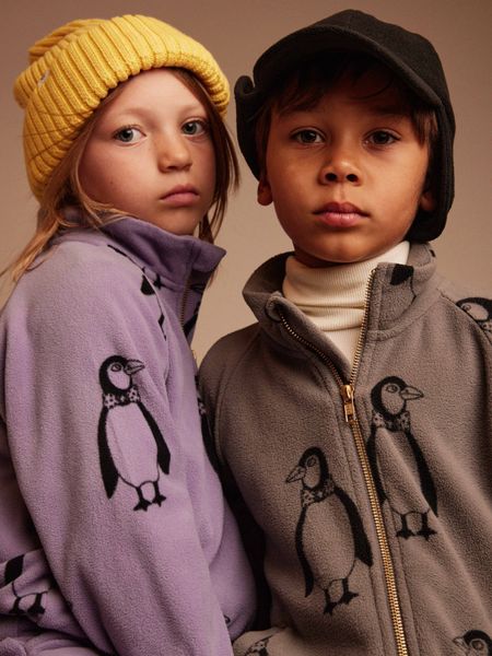 Two children wearing fleece jackets featuring a Penguin print.