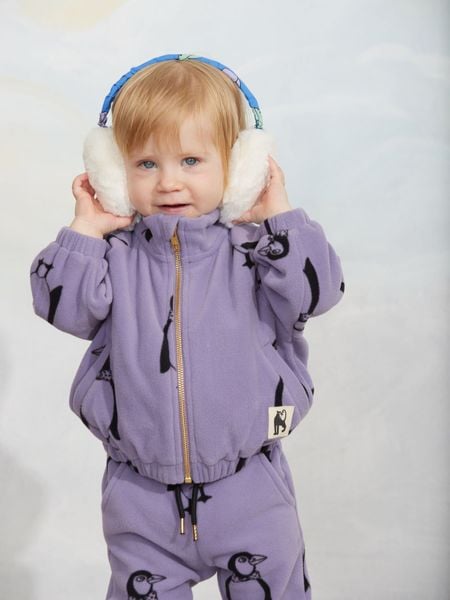 Purple zip-up fleece jacket with a Penguin print, worn by a child wearing white earmuffs.