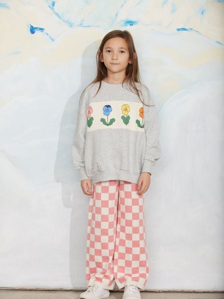 Pink and white chess check knitted trousers worn with a grey pansy print sweatshirt.