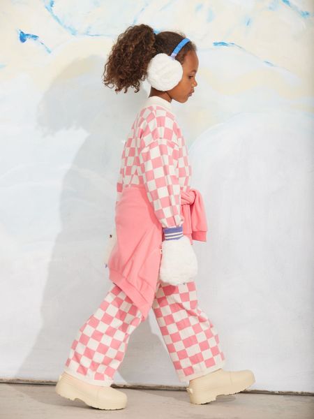 Pink chess check knitted trousers and top worn with white fluffy earmuffs and mittens.