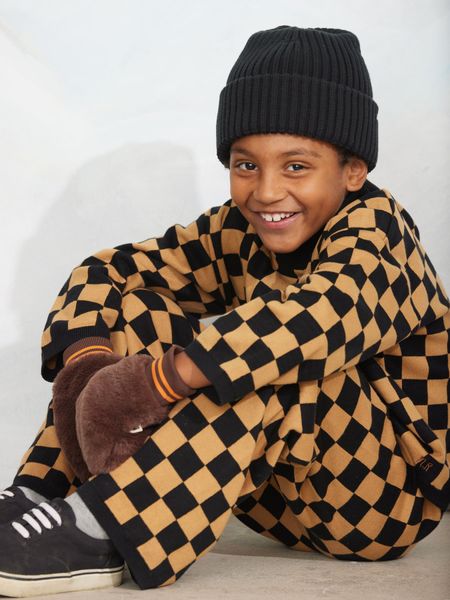 Brown and black chess check knitted top and trousers, worn with a black beanie and brown mittens.