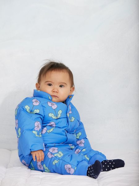 Blue padded citypuffer featuring a purple Viola flower print, worn by a sitting child.