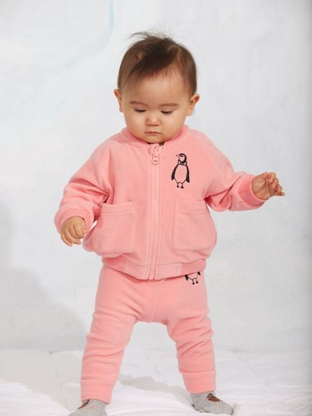 Pink microfleece trousers and matching zip jacket with a penguin embroidery, worn by a child.
