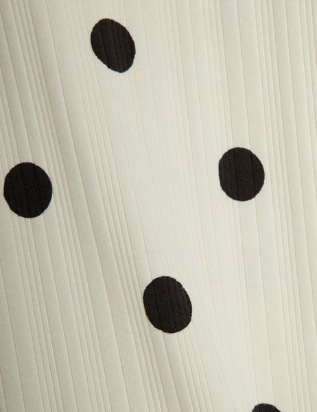 Close-up of an off-white ribbed fabric featuring a large black dot pattern.