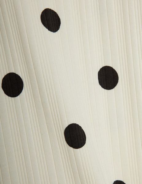 Close-up of off-white ribbed fabric featuring a black Dots print.