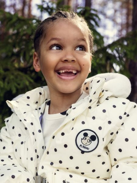 Close-up of an off-white heavy puffer jacket with black polka dots and a Ritzratz patch.