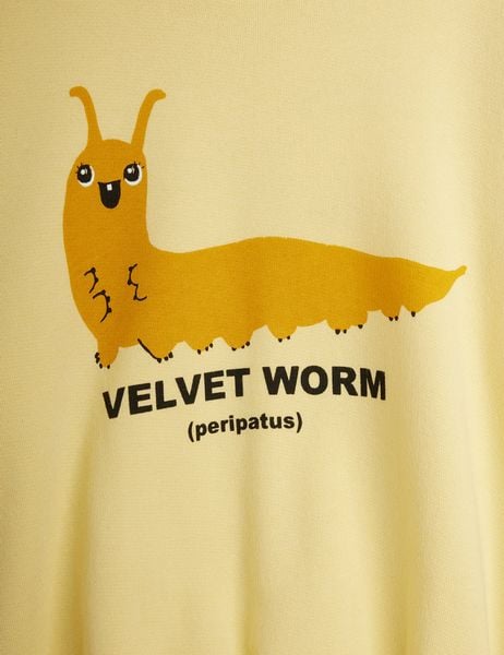 Close-up of a yellow sweatshirt featuring a smiling Velvet worm print and black text.