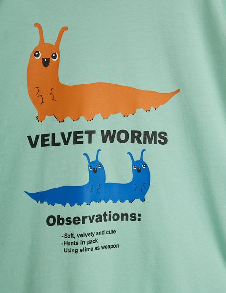 Close-up of a green T-shirt featuring an orange and two blue velvet worms with text.