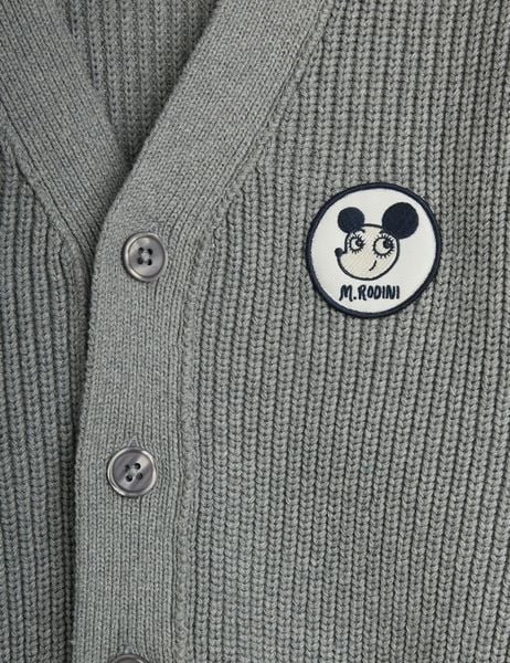 Close-up of a grey knitted cardigan featuring a circular Ritzratz patch and buttons.