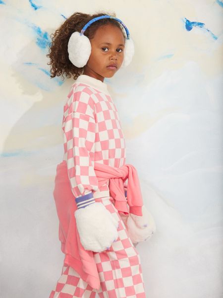 Pink and white chess check knitted sweater worn with white fluffy earmuffs and mittens.