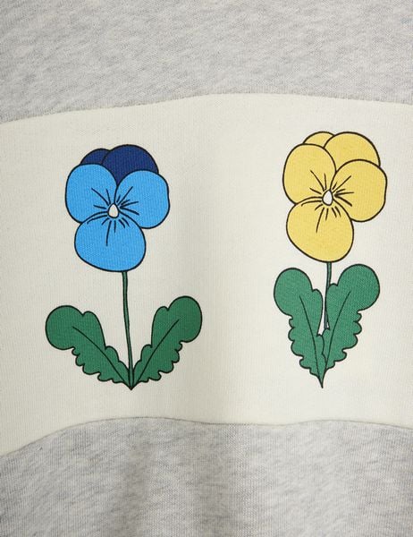 Close-up of a blue and a yellow Viola flower print on an off-white panel of a grey melange sweatshirt.