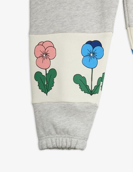 Close-up of a grey sweatpants leg featuring a white panel with pink and blue Violas print and elastic cuff.