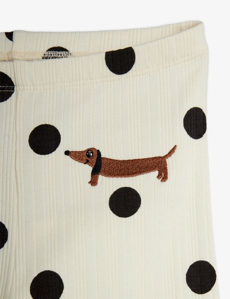 Close-up of off-white ribbed fabric with a black dots print and an embroidered brown dog motif.