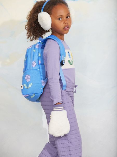 Purple textured frill trousers worn with a blue floral backpack and white fuzzy mittens.