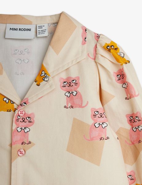 Close-up of a cream blouse with a pink and yellow Kittens print, camp collar, and buttons.