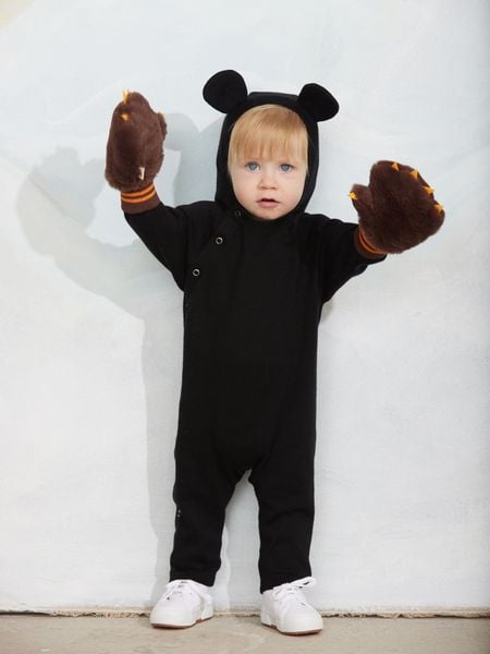 Black fine knit baby jumpsuit featuring a mouse-ear hood, snap buttons, and worn with brown fuzzy claw mittens.