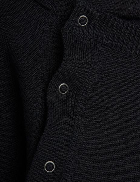 Metal snap button and ribbed neckline detail on a black fine knit baby jumpsuit.