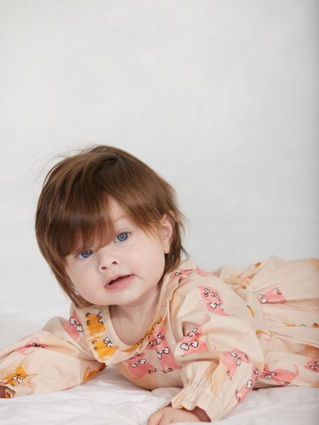 Beige bodysuit featuring a Kittens print and ruffled collar, worn by a baby lying on their stomach.