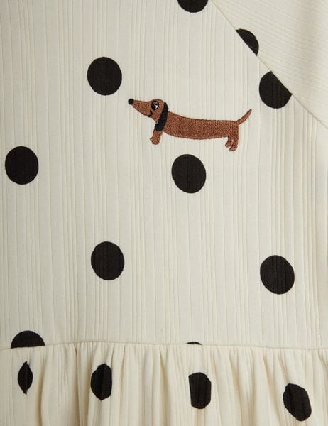 Close-up of an off-white ribbed dress with black polka dots and an embroidered dachshund dog.