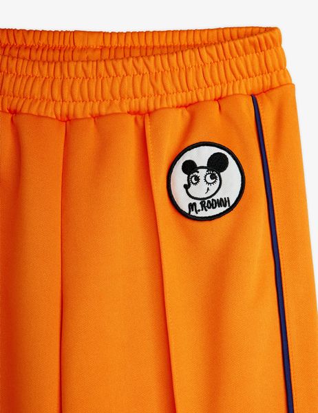 Orange recycled polyester trousers with a Ritzratz patch, featuring an elastic waistband and striped side piping.