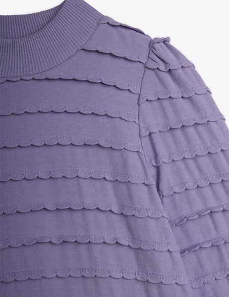 Close-up of a purple textured dress featuring layered horizontal scalloped frills across the chest and sleeves.