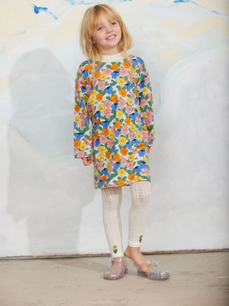 Long-sleeved dress featuring a colorful Viola flower print and a ribbed collar, worn with white patterned tights.