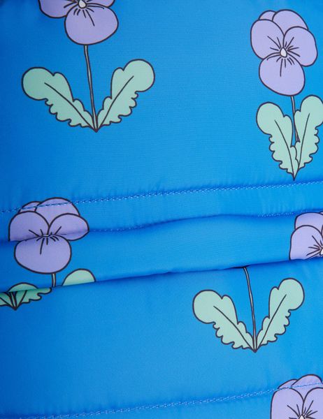 Close-up of blue padded fabric featuring a purple Violas print and quilted texture.