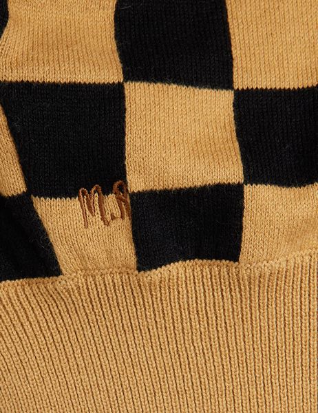 Close-up of brown and black chess check knitted fabric featuring small M.R embroidery and a ribbed texture.