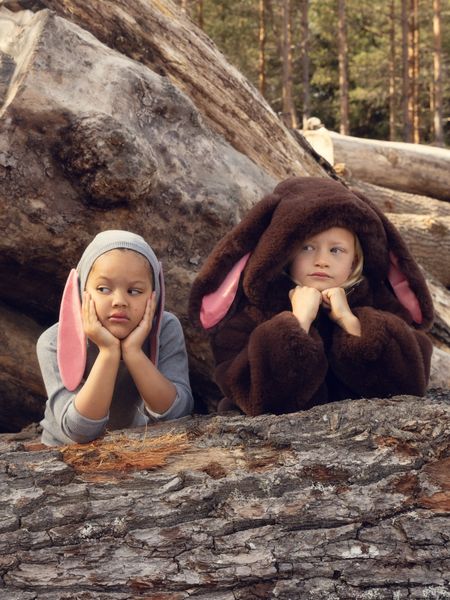 Brown faux-fur jacket with a rabbit-ear hood, worn by a child sitting outdoors.