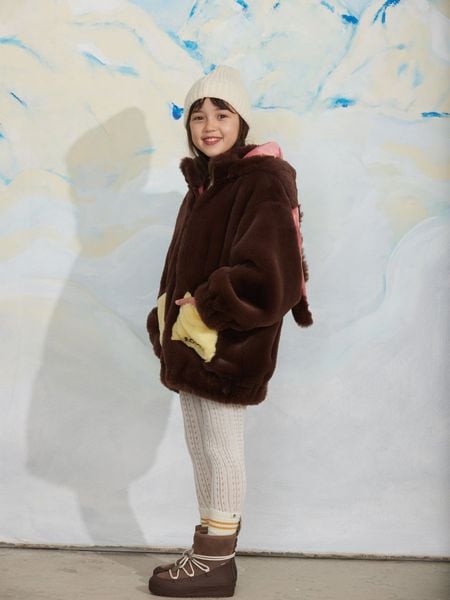 Brown faux fur jacket with a rabbit-ear hood and yellow front pockets, worn by a child.