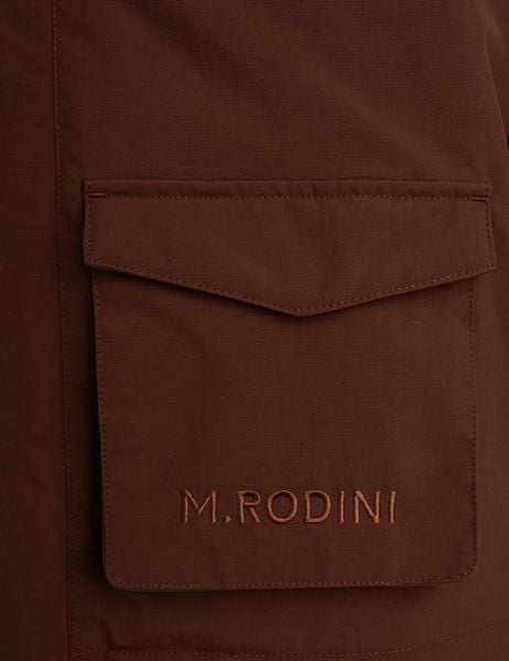 Detail of a brown padded parka showing a front pocket with tonal M.RODINI embroidery.