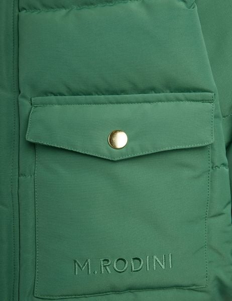 Close-up of a green puffer jacket pocket featuring a gold snap button and logo embroidery.