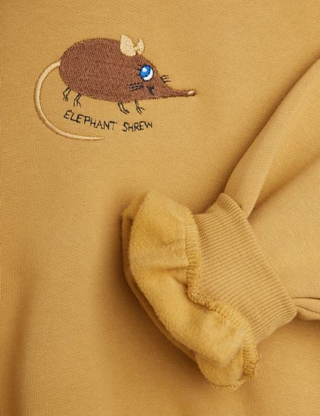 Beige sweatshirt close-up with a ribbed cuff and brown Elephant Shrew embroidery.