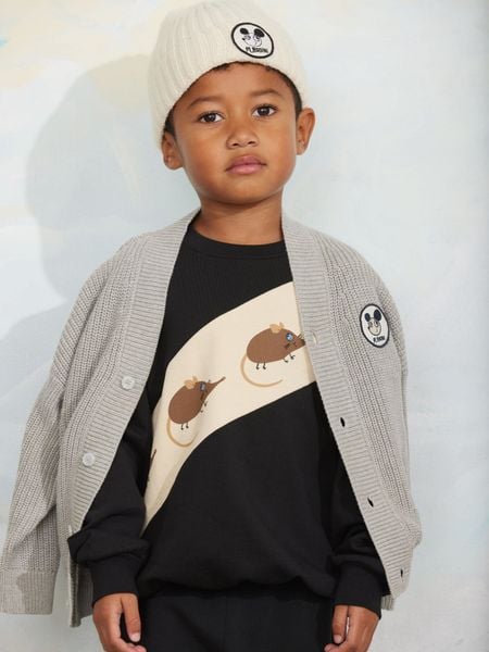 Black sweatshirt featuring a diagonal panel with elephant shrew print, worn by a child wearing a grey cardigan and beanie.
