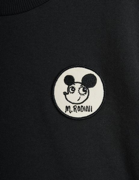 Circular white Ritzratz patch featuring M. RODINI text on a black T-shirt.