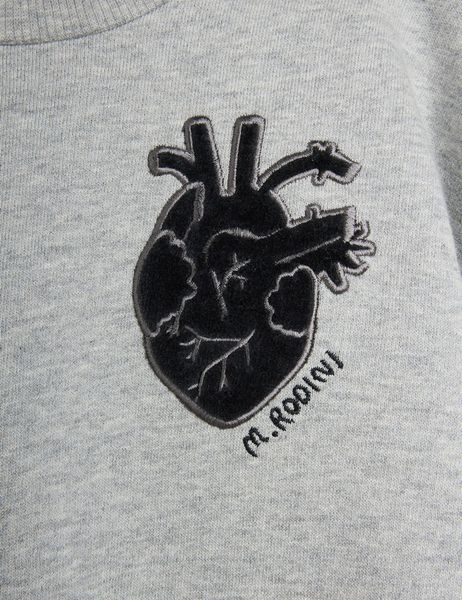 Close-up of a black anatomical heart application and M. Rodini embroidery on grey melange fabric.