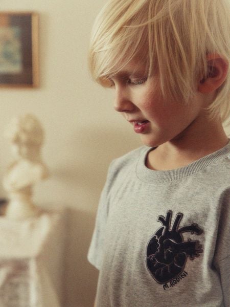 Close-up of a child wearing a grey melange t-shirt with a heart application on the chest.