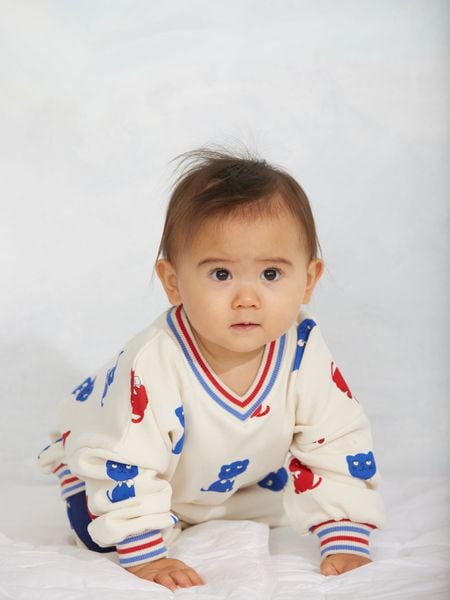 Off-white sweatshirt with Kittens print, worn by a baby.