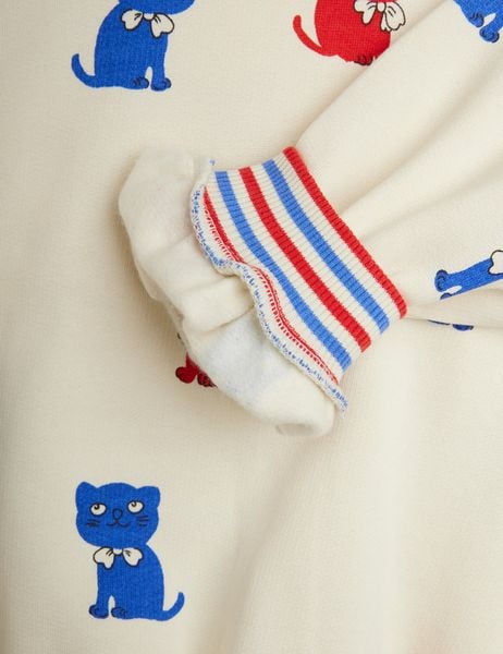 Ribbed striped cuff in red and blue on an off-white sweatshirt featuring a blue Kittens print.