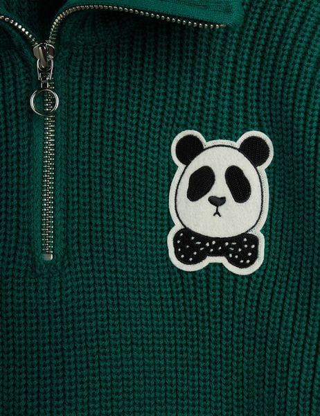 Close-up of green chunky knit sweater featuring a silver half-zip and a Panda patch.