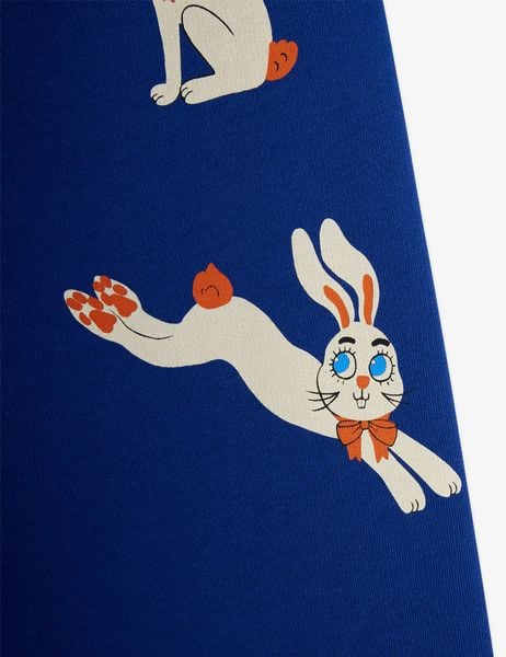Leaping white Rabbit print with an orange bow tie on blue sweatpants, close-up.