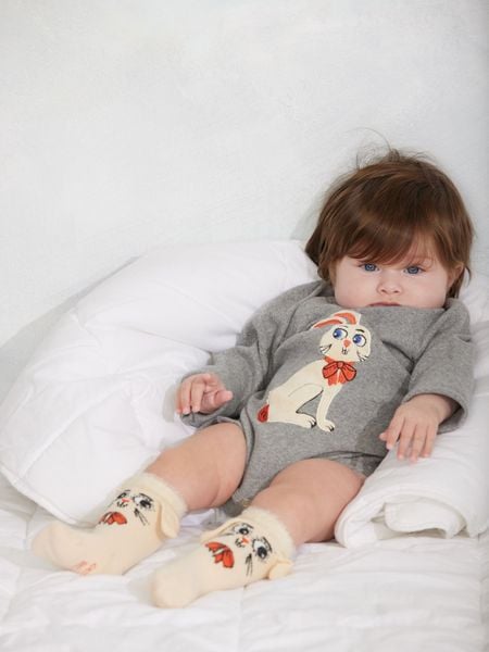 Grey melange long-sleeved bodysuit featuring a rabbit application, worn by a baby lying down.